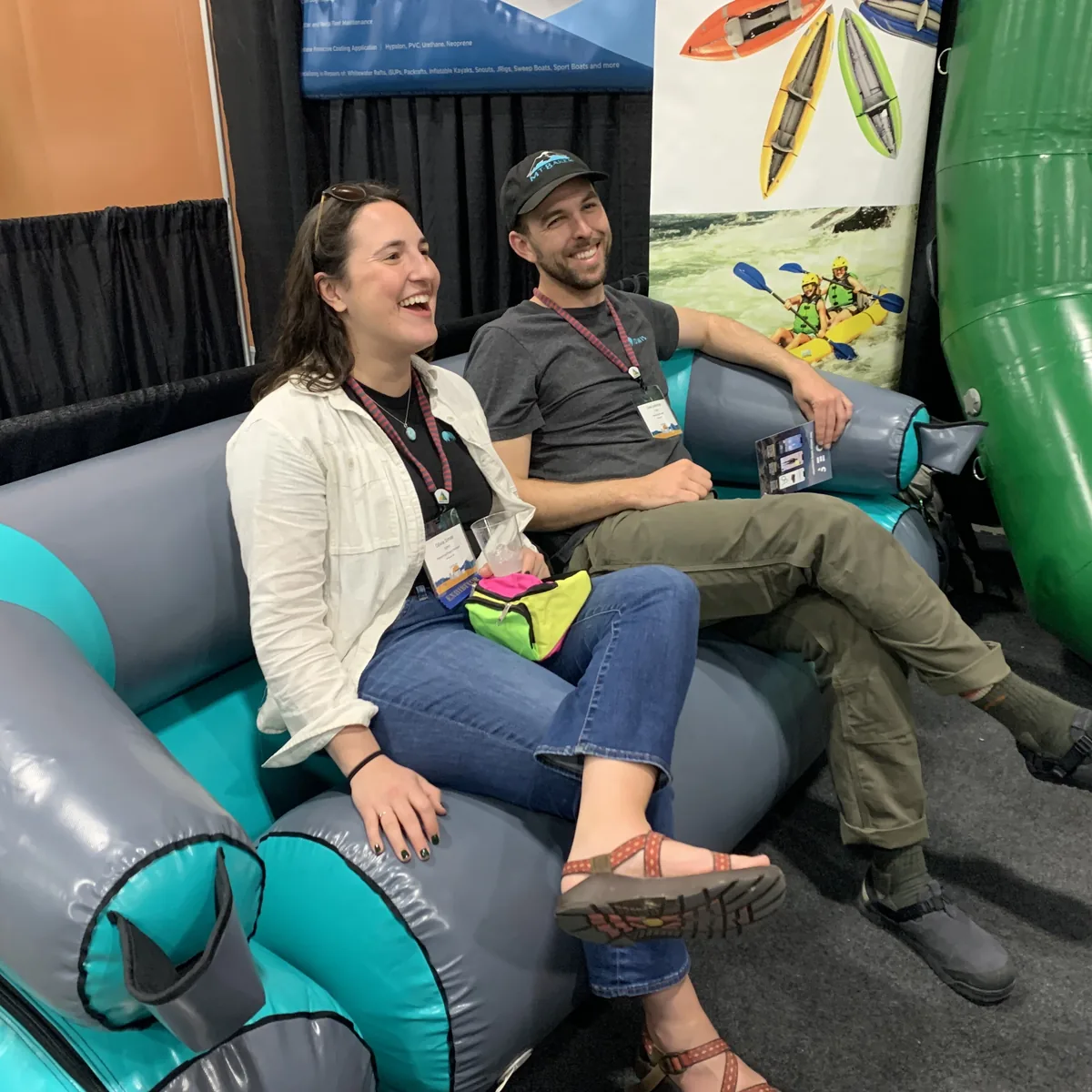 Two TOMIS team members laughing on an inflatable raft at a conference