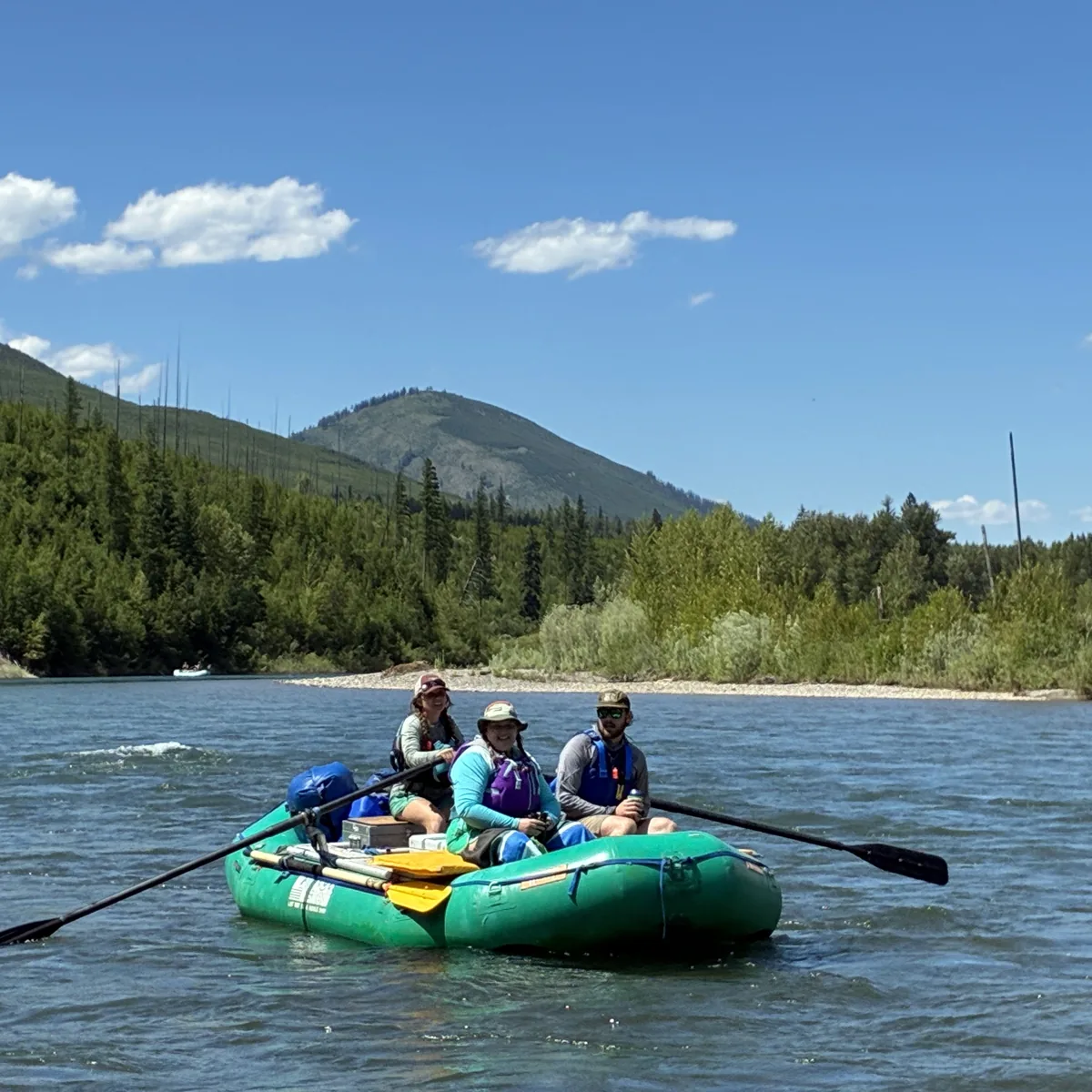 TOMIS team members rowing a raft down a mountain river